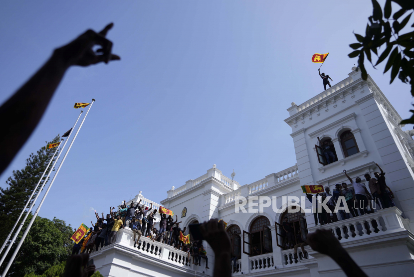  Seorang pengunjuk rasa Sri Lanka mengibarkan bendera nasional dari atap kantor Perdana Menteri Sri Lanka Ranil Wickremesinghe, menuntut dia mengundurkan diri setelah presiden Gotabaya Rajapaksa melarikan diri dari negara itu di tengah krisis ekonomi di Kolombo, Sri Lanka, Rabu, 13 Juli 2022. Presiden Sementara Sri Lanka Ranil Wickremesinghe telah mengumumkan keadaan darurat. 