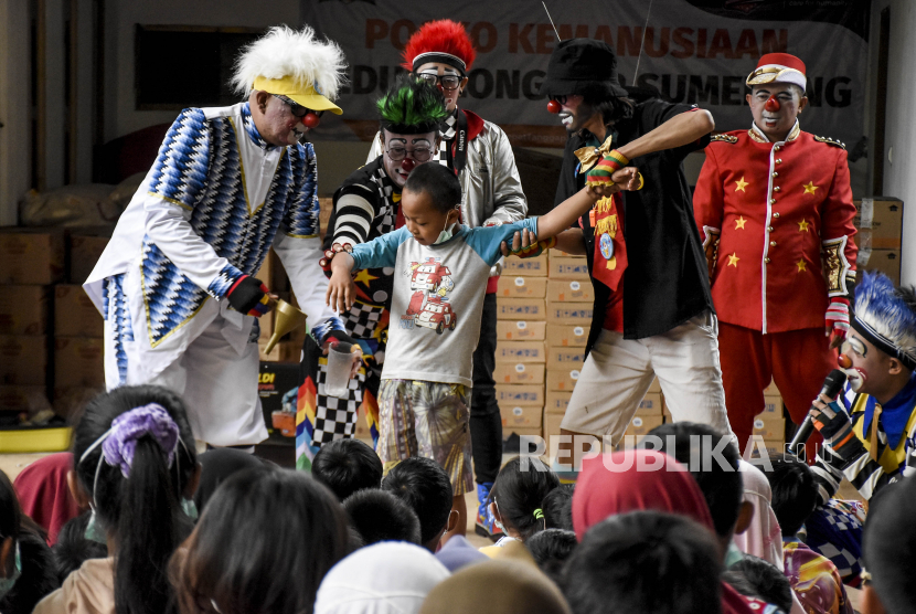 Anggota Badut Nyentrik Cimahi Bandung Sauyunan (Necis) menghibur anak-anak korban bencana tanah longsor di posko pengungsian, Desa Cihanjuang, Kecamatan Cimanggung, Kabupaten Sumedang, Jumat (22/1/2021).