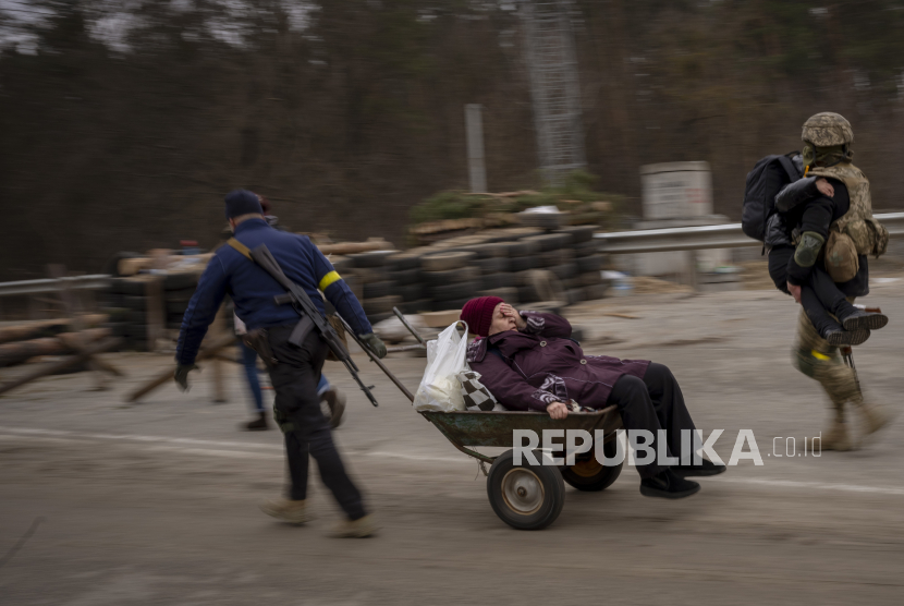  Seorang tentara Ukraina dan seorang anggota milisi membantu sebuah keluarga yang melarikan diri menyeberangi sungai Irpin di pinggiran Kyiv, Ukraina, Sabtu, 5 Maret 2022.