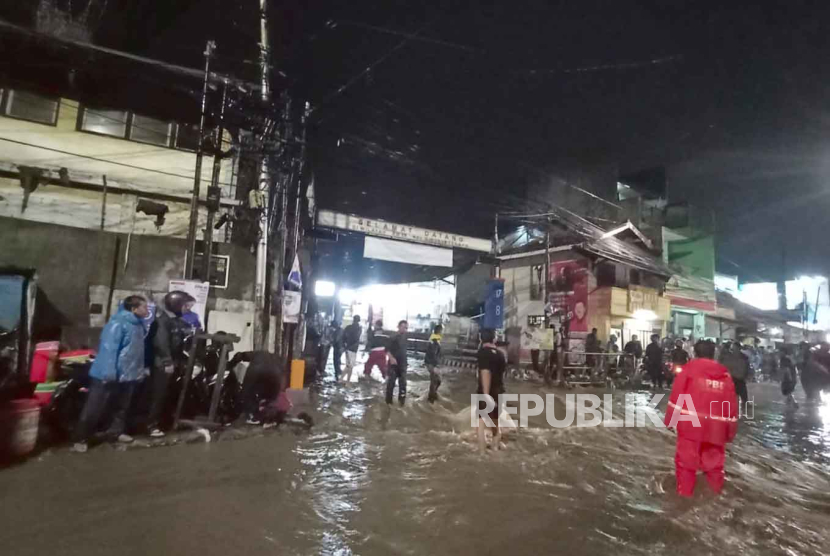 Hujan deras menyebabkan luapan sungai Cimahi ke badan jalan di Jalan Mahar Martanegara, Selasa (5/12/2023). Sebuah angkot berisi penumpang di Cimahi, Jabar dievakuasi karena terjebak banjir.