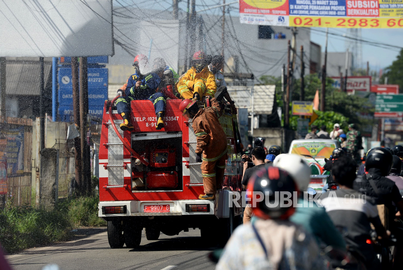 Petugas pemadam kebakaran menyemprotkan cairan disinfektan di jalan Raya Parung-Bogor, Bogor, Jawa Barat, Selasa (31/3). Tim gabungan terdiri dari TNI-Polri, BPBD, Satpol-PP dan Pemadam Kebakaran melakukan penyemprotan disinfektan di jalan protokol dan fasilitas umum untuk mengantisipasi penyebaran COVID-19
