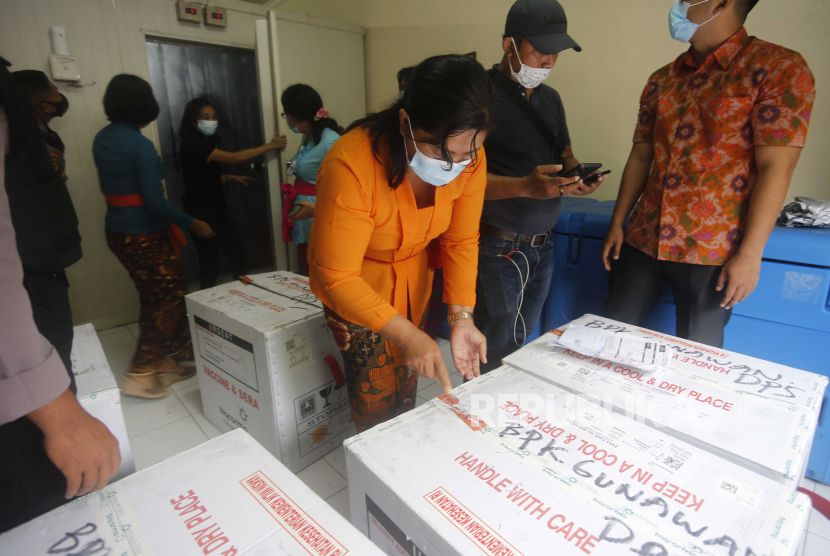 Petugas kesehatan mencentang kotak berisi vaksin virus corona yang dikembangkan oleh Sinovac Biotech China saat mereka tiba di Bali, Indonesia pada Kamis, 7 Januari 2021. Tidak semua orang memenuhi kriteria untuk mendapatkan vaksin Covid-19 yang dikembangkan Sinovac.