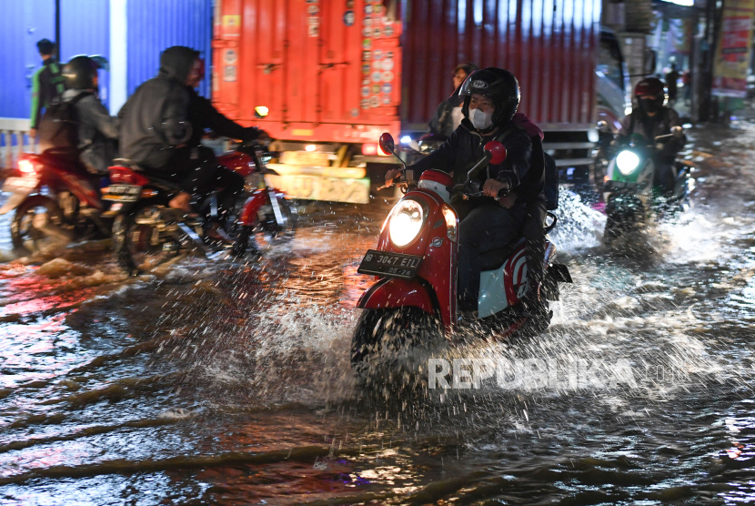 Pengendara melintasi Jalan Sawangan yang tergenang akibat luapan Kali Licin di Mampang, Depok, Jawa Barat, Jumat (7/10/2022). 