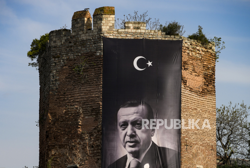 Spanduk raksasa Presiden Turki dan calon presiden dari Aliansi Rakyat Recep Tayyip Erdogan dipajang di tembok kota bersejarah, di Istanbul, Turki, Sabtu (22/4/2023). 