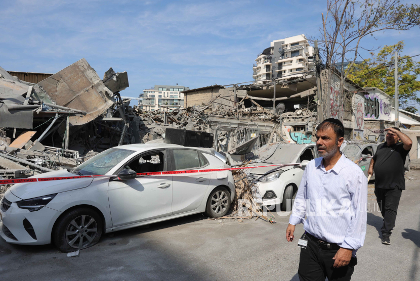 Warga melihat rumah dan kendaraan yang hancur di Tel Aviv, 8 Oktober 2023.