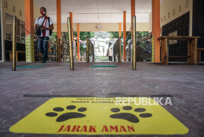 Warga melintas di depan pintu masuk Taman Satwa Taru Jurug (TSTJ) yang diberi tanda menjaga jarak di Solo, Jawa Tengah, Jumat (12/6/2020). Kebun binatang TSTJ akan dibuka kembali pada 19 Juni 2020 dan menerapkan aturan normal baru sesuai protokol kesehatan yaitu salah satunya dengan pembatasan jumlah kunjungan wisatawan