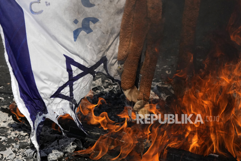 Gambar bendera Israel dibakar di samping boneka monyet saat unjuk rasa. 
