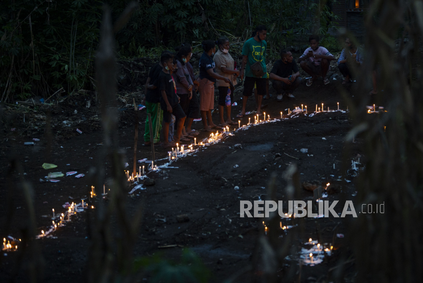 Sejumlah warga menyalakan lilin saat berziarah di tempat pemakaman massal korban tanah longsor di Desa Nelelamadike, Kecamatan Ile Boleng, Kabupaten Flores Timur, Nusa Tenggara Timur (NTT), Rabu (7/4/2021). Sebagian besar dari 55 orang korban meninggal akibat tanah longsor di desa tersebut dimakamkan di lokasi tersebut. 