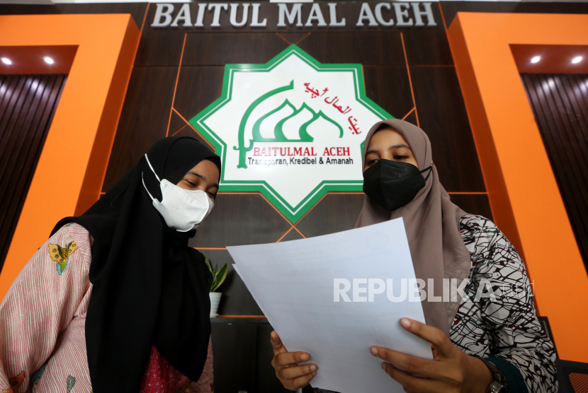 Petugas lembaga penyaluran zakat Baitul Mal (kanan) memeriksa berkas permohonan bantuan zakat dari warga di kantor Baitul Mal Aceh, Banda Aceh, Aceh, Kamis (9/12/2021). Untuk diakui sebagai lembaga formal, LAZ wajib memiliki izin operasional. Ilustrasi.