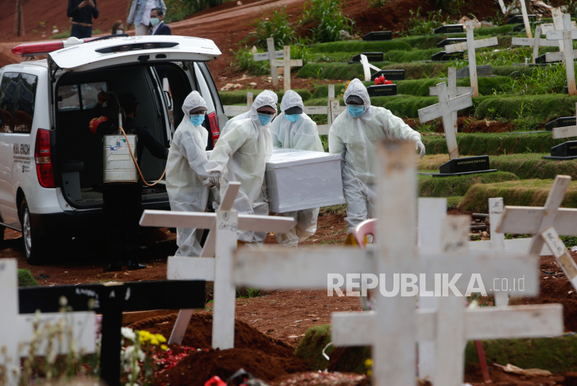  Pekerja dengan perlengkapan pelindung membawa peti mati seseorang yang meninggal dengan COVID-19 saat pemakaman di Pemakaman Pondok Ranggon di Jakarta, Indonesia, 30 November 2020. 
