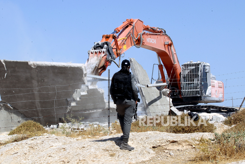 Personel polisi perbatasan Israel berjaga ketika buldoser Israel menghancurkan bangunan Palestina di kota Hebron, Tepi Barat, 21 Juli 2020. Tentara Israel menghancurkan rumah-rumah warga Palestina tanpa izin yang diperlukan untuk membangun unit perumahan atau infrastruktur di Area C Tepi Barat. 