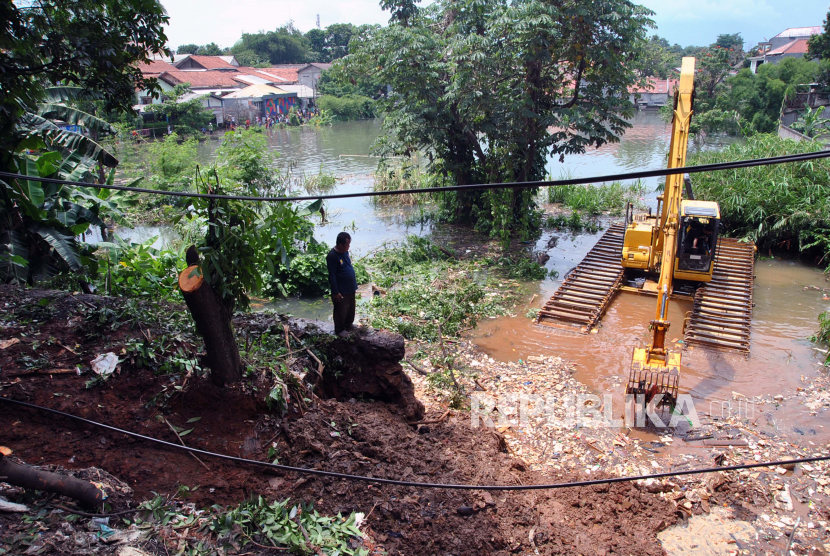 Petugas Dinas Bina Marga dan Sumber Daya Air Kota Bogor menggunakan alat berat untuk mengeruk tanah longsor yang menutupi saluran air drainase penyebab banjir di Perumahan Griya Cimanggu Indah, Kelurahan Kedung Badak, Tanah Sareal, Kota Bogor, Jawa Barat, Senin (26/10/2020). Hujan deras dengan intensitas tinggi yang terjadi di wilayah Bogor pada Sabtu (24/10/2020) tersebut menyebabkan 17 rumah di perumahan tersebut terendam banjir luapan sungai Ciliwung dengan ketinggian 50 sentimeter hingga satu meter akibat tanah longsor yang menutupi saluran air drainase. 