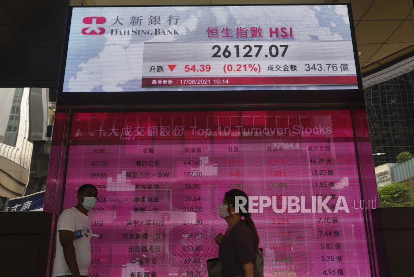 Orang-orang berjalan melewati papan elektronik bank yang menunjukkan indeks saham Hong Kong di Bursa Efek Hong Kong Selasa, 17 Agustus 2021. Lonjakan kasus virus corona membuat Bank Dunia pangkas prediksi pertumbuhan ekonomi. Ilustrasi.