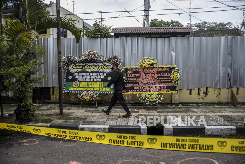 Anggota kepolisian berjalan di depan karangan bunga di Mapolsek Astana Anyar, Jalan Astana Anyar, Kota Bandung, Kamis (8/12/2022). Anggota Komisi III DPR sebut polisi harus mengusut tuntas bom bunuh diri di Bandung.