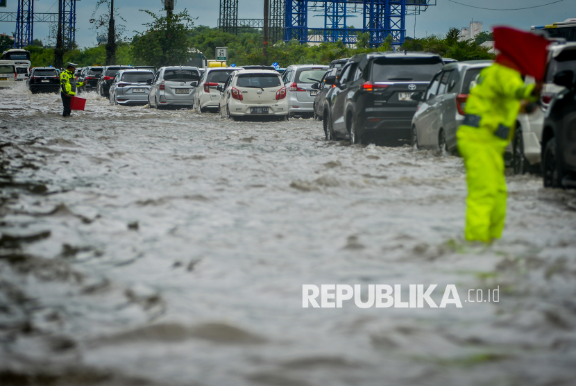 Polisi mengatur lalu lintas kendaraan saat banjir di Jalan Tol Sedyatmo, Cengkareng, Jakarta, Rabu (29/1/2025). Jalan tol yang merupakan akses menuju Bandara Soekarno-Hatta tersebut terendam banjir setinggi 20-30 sentimeter akibat tingginya intensitas hujan. 