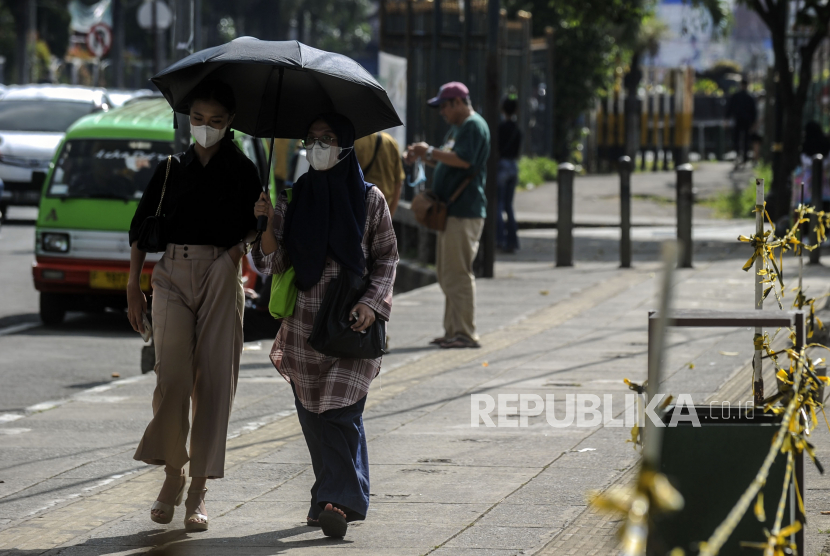 Warga menggunakan payung saat melintasi kawasan Alun-Alun Kota Bogor, Jawa Barat, Kamis (12/5/2022). 