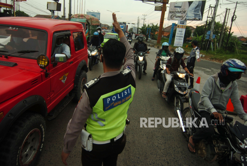 Personel kepolisian mengatur arus lalu lintas di pos penyekatan jalur Pantura, Tegal, Jawa Tengah, Jumat (7/5/2021). Pada hari kedua pemberlakukan penyekatan pemudik, jakur Pantura terpantau ramai lancar didominasi truk dan kendaraan roda dua masyarakat setempat. 