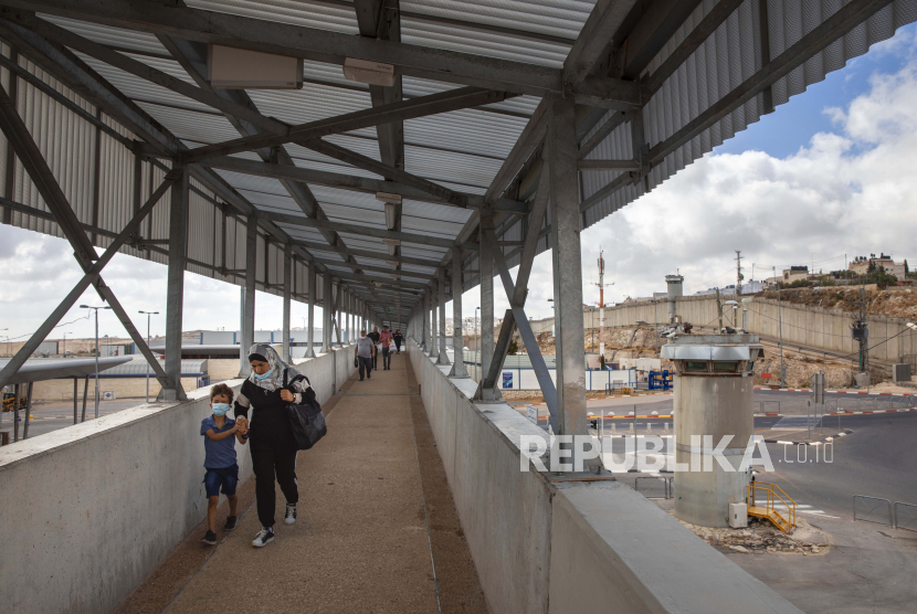 Warga Palestina melintasi jembatan di pos pemeriksaan Qalandia antara kota Ramallah di Tepi Barat dan Yerusalem. Tentara Israel telah mengerahkan dua batalion tentara untuk berjaga di pos pemeriksaan Qalandia dan Bethlehem selama bulan puasa Ramadhan. Pasukan tambahan itu akan dikerahkan setiap Jumat hingga akhir Ramadhan.