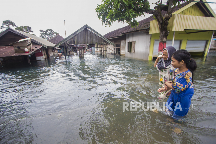 Warga melintasi banjir yang melanda Desa Banua Raya di Kabupaten Tanah Laut, Kalimantan Selatan, Senin (11/1/2021).  Berdasarkan data yang telah di himpun aparat desa Banua Raya, sebanyak 2.907 Jiwa terdampak banjir akibat luapan sungai Bati Bati. 