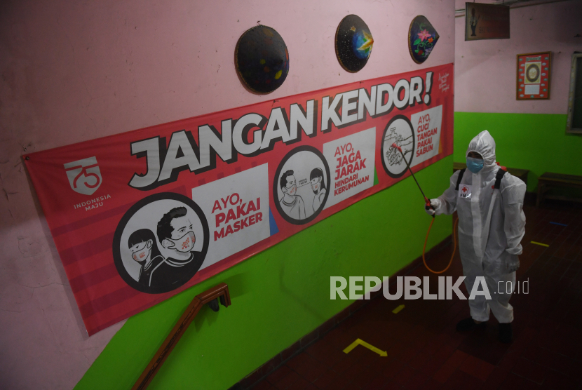 Kementerian Kesehatan (Kemenkes) melaporkan hingga Jumat (21/1/2022), sudah ada 1.078 kasus omicron. Foto: Petugas Palang Merah Indonesia (PMI) menyemprotkan disinfektan di SMPN 43 Jakarta, Kamis (20/1/2022). 