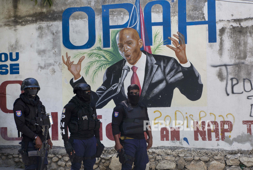 Polisi berdiri di dekat mural yang menampilkan Presiden Haiti Jovenel  Moise,di dekat kediaman pemimpin tempat dia dibunuh oleh orang-orang bersenjata pada dini hari di Port-au-Prince, Haiti, Rabu, 7 Juli 2021.