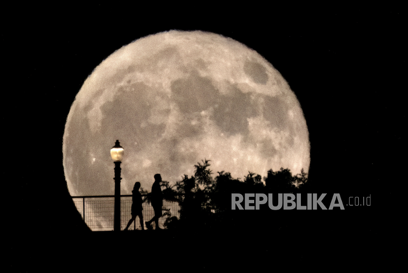 Orang-orang berjalan di depan bulan purnama super (supermoon) di Observatorium Griffith di Los Angeles, Senin, 19 Agustus 2024.
