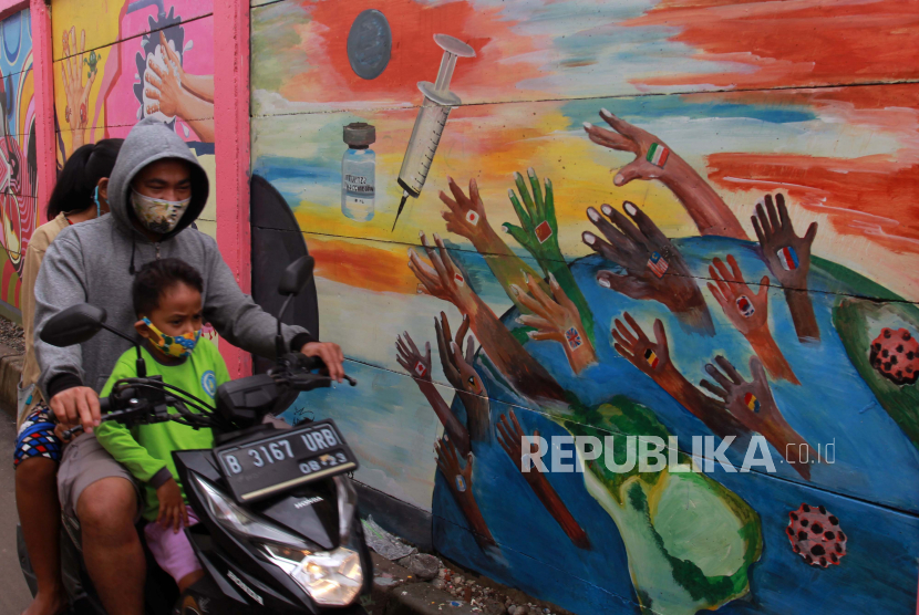 Pengendara melintas disamping mural yang bertemakan kampanye melawan COVID -19 yang ada di kawasan Tanah Tinggi, Tangerang, Banten, Rabu (20/1/2021). Kampanye dalam bentuk mural melawan COVID-19 dan imbauan 3M yaitu Memakai masker, Mencuci tangan dengan sabun serta Menjaga jarak tersebut dan Vaksinisasi merupakan bagian dari  mengedukasi berbagai cara dalam melawan Covid-19. 