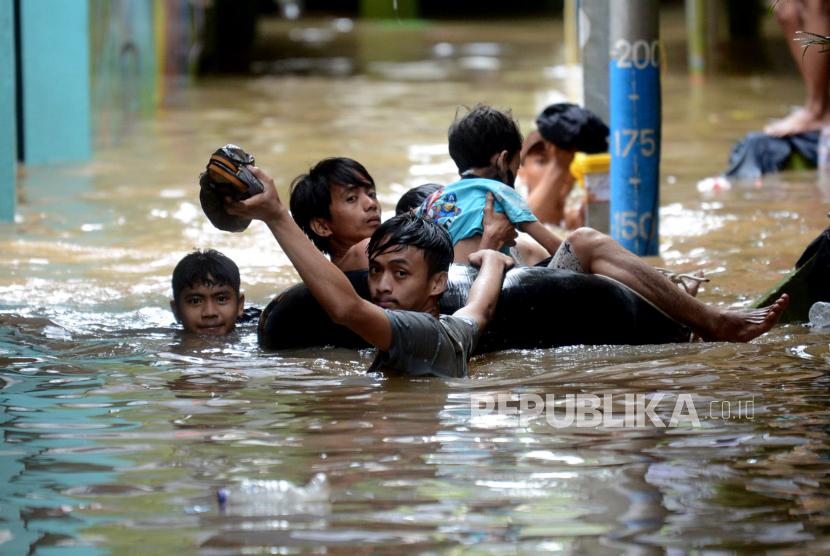 Seorang warga berenang ketika banjir merendam di kawasan Kebon Pala, Kampung Melayu, Kecamatan Jatinegara, Jakarta Timur, Senin (27/2/2023).