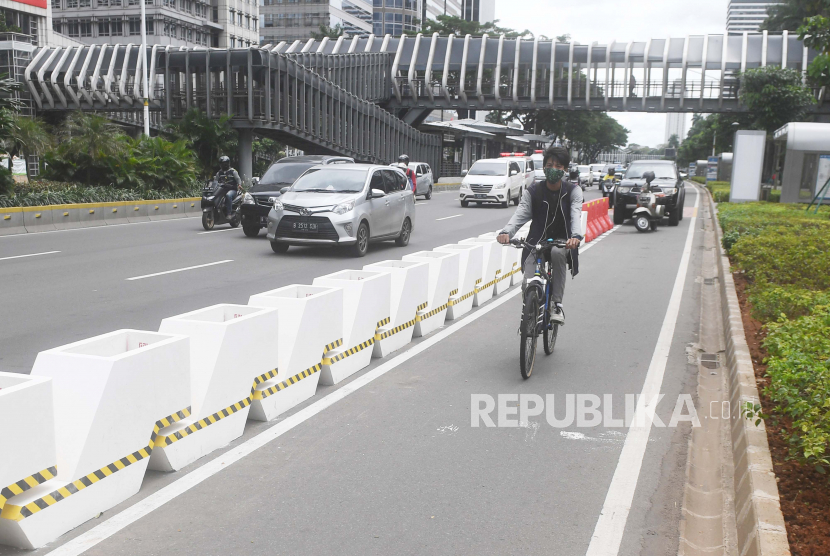 Pesepeda melintasi jalur sepeda yang diberikan pembatas jalur permanen di Jalan Jenderal Sudirman, Jakarta, Rabu (24/2/2021).
