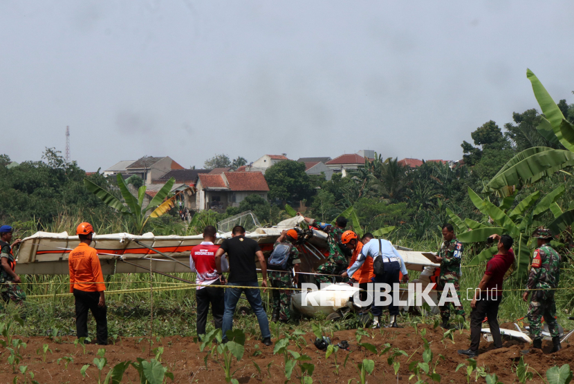 Petugas Basarnas bersama prajurit TNI AU berusaha mengevakuasi bangkai pesawat latih sipil Microlight Fixedwing Quicksilver GT500 dengan register PK-S126 yang jatuh di perkebunan warga, TPU Astana, Ciampea, Kabupaten Bogor, Jawa Barat, Ahad (3/8/2025). Pesawat latih sipil milik Federasi Aero Sport Indonesia (FASI) yang mengalami hilang kontak pada pukul 09.19 WIB ditemukan jatuh di sekitar TPU tersebut dan menyebabkan satu orang meninggal dunia dan satu orang mengalami luka berat dan dibawa ke RSAU dr. M. Hassan Toto, Bogor. 