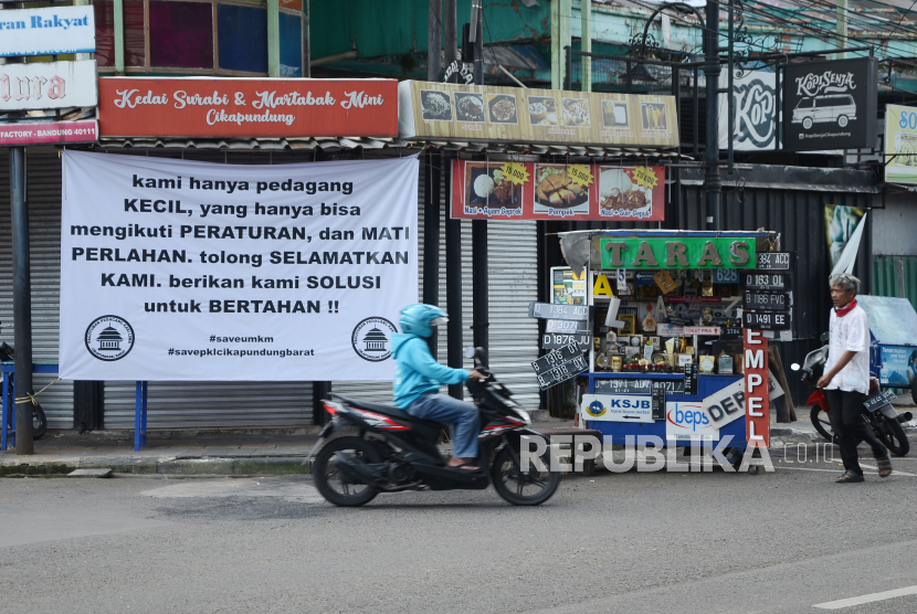 Sejumlah spanduk dipasang oleh Paguyuban Pedagang Kaki Lima terkait dampak PPKM yang dirasakan para pedagang kaki lima (PKL) di Jalan Cikapundung Barat, Kota Bandung, Jumat (16/7). Spaduk tersebut berisi harapan kepada pemerintah agar ada kebijakan dan solusi untuk mengatasi masalah yang dihadapi para pedagang kecil seperti PKL di saat penerapan PPKM Darurat.