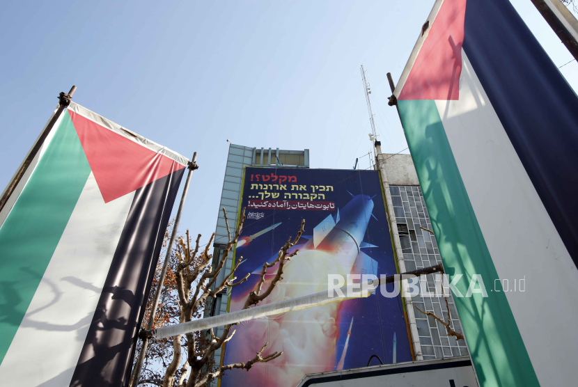 Bendera Palestina dan papan reklame bergambar rudal Iran dengan pesan dalam bahasa Persia dan Ibrani. 