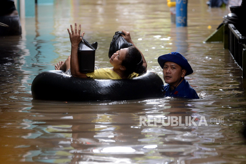 Petugas membantu warga melintasi melintasi banjir yang merendam kawasan Kebon Pala, Kampung Melayu, Jatinegara, Jakarta Timur. Sekda DKI sebut Pemprov akan membangun drainase untuk mengatasi banjir di Jakarta.