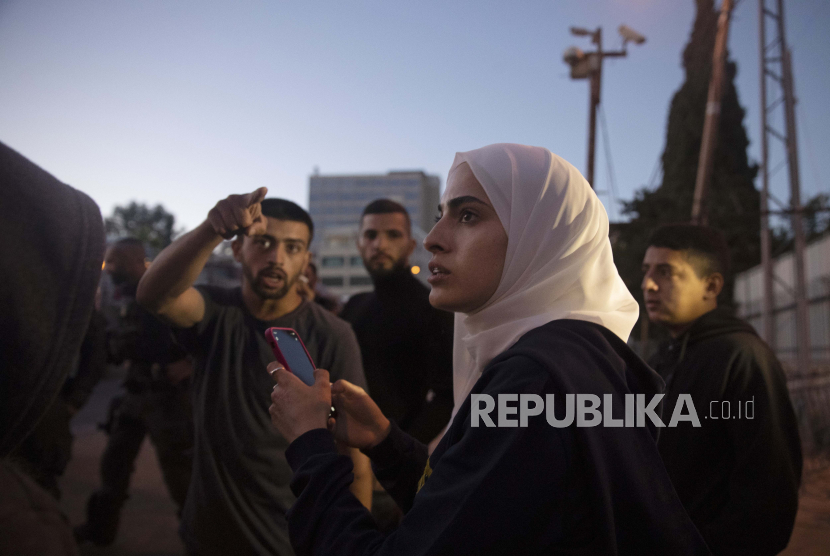 Aktivis Palestina Muna al-Kurd, tengah, berdiri dengan aktivis lain ketika polisi Israel mendekati teman-teman mereka memperbaiki mural yang dirusak oleh pemukim Yahudi, di lingkungan Sheikh Jarrah di Yerusalem timur, di mana keluarga Palestina menghadapi penggusuran dari rumah mereka oleh Israel pemukim, Senin, 24 Mei 2021. 