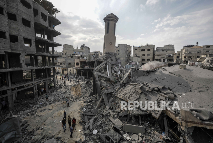 Warga Palestina berjalan di reruntuhan gedung yang hancur akibat serangan udara militer Israel di Jalur Gaza, Senin, 9 Oktober 2023.