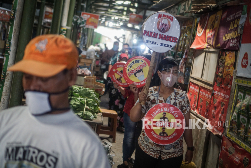 Petugas pasar berkeliling dengan membawa poster imbauan untuk mengenakan masker di Pasar Harjodaksino, Solo, Jawa Tengah. Survei BPS menemukan warga Solo masih abai protokol kesehatan Covid-19. Ilustrasi.