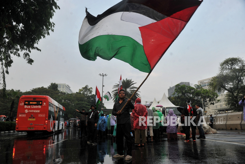 Massa mengibarkan bendera Palestina.