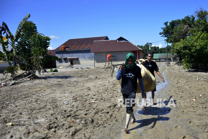 Warga melewati material lumpur sambil membawa barang miliknya di Desa Radda, Kabupaten Luwu Utara, Sulawesi Selatan, Sabtu (19/7/2020). Pasca banjir bandang sejumlah warga yang terdampak mulai mengambil barangnya yang masih bisa digunakan. 