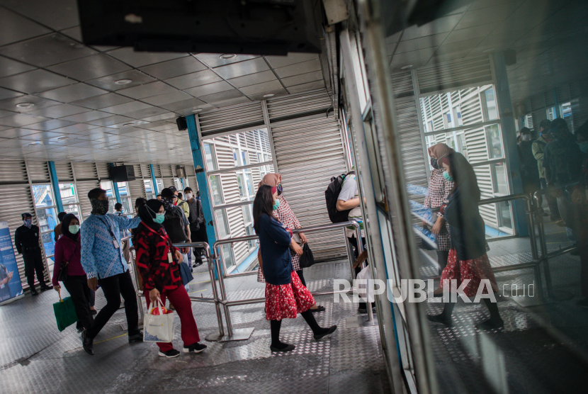 Sejumlah calon penumpang menerapkan jarak sosial saat akan menaiki bus Transjakarta di Halte Harmoni, Jakarta