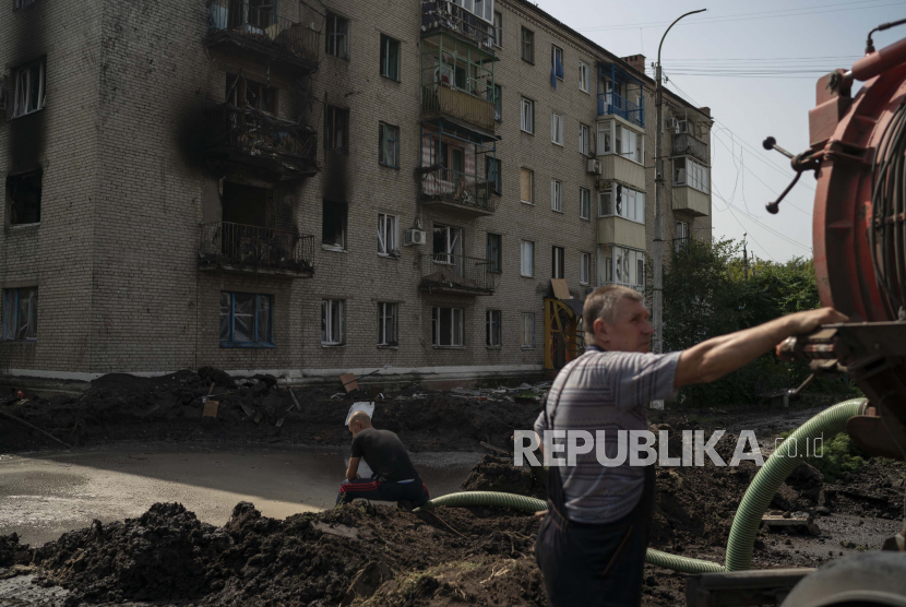 Pekerja mengalirkan air dari kawah yang dibuat oleh ledakan yang merusak bangunan tempat tinggal setelah serangan Rusia di Slovyansk, Ukraina, Minggu, 28 Agustus 2022.