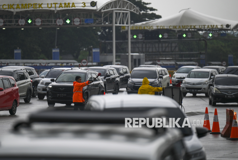 Petugas mengarahkan kendaraan saat mengatur lalu lintas di Gerbang Tol Cikampek Utama 1, Kabupaten Karawang, Jawa Barat, Rabu (1/1/2025). Berdasarkan data PT Jasa Marga arus lalu lintas di Gerbang Tol Cikampek Utama dari arah Palimanan menuju Jakarta hingga sore tercatat 19.563 kendaraan. 