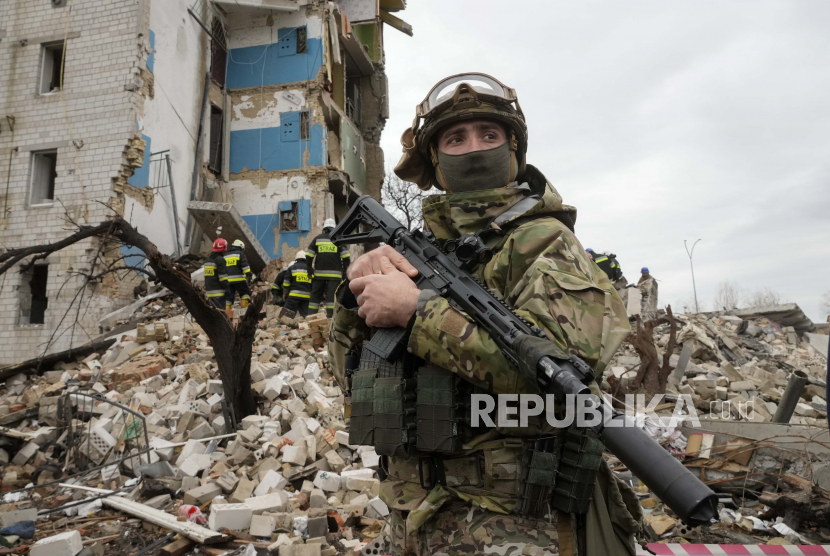 Seorang tentara Ukraina berdiri dengan latar belakang sebuah rumah apartemen yang hancur dalam penembakan Rusia di Borodyanka, Ukraina, Rabu, 6 April 2022.