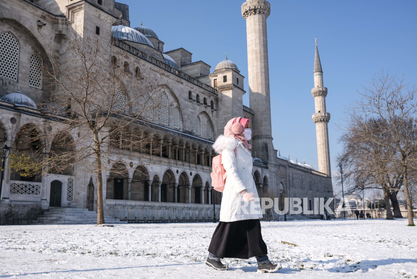 Seorang wanita berjalan di taman Masjid Suleymaniye pada hari bersalju di Istanbul, Turki, 18 Januari 2021.