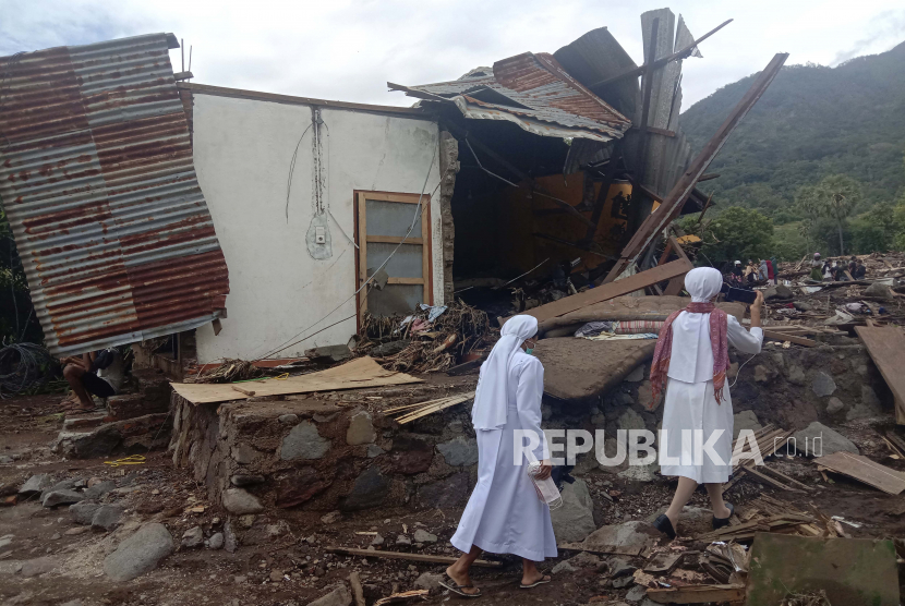  Para biarawati berjalan melewati sebuah rumah yang rusak di sebuah desa yang terkena banjir di Ile Ape di Pulau Lembata, provinsi Nusa Tenggara Timur, Indonesia, Selasa, 6 April 2021.