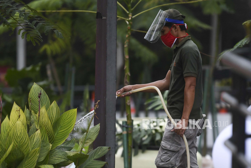 Seorang pekerja mengenakan masker dan pelindung wajah menyiram tanaman di kawasan Senayan Jakarta, Selasa (9/6/2020). Penggunaan masker secara luas di dunia, termasuk kebijakan seperti PSBB bisa membantu mencegah terjadinya gelombang kedua Covid-19.