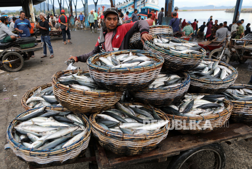 Seorang nelayan memamerkan hasil tangkapannya untuk dijual di tengah pandemi Covid-19 di pasar ikan tradisional.