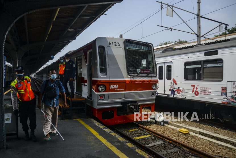 Petugas menuntun penyandang tuna netra di dekat gerbong KRL Commuter Line bertemakan Kemerdekaan Republik Indonesia ke-76 di Stasiun Jakarta Kota, Jakarta, Selasa (17/8). Transportasi merupakan pendorong ekonomi dan tulang punggung dari proses distribusi orang dan barang. 