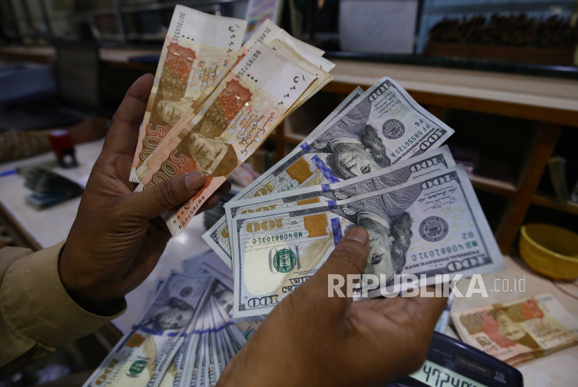 Petugas penukaran mata uang menyortir dolar AS dan rupee Pakistan di tokonya di Karachi, Pakistan, 12 Januari 2023. 
