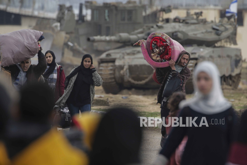Pengungsi Palestina bergerak melewati tank Israel setelah tentara Israel menyuruh penduduk kamp Khan Yunis meninggalkan rumah mereka dan menuju kamp Rafah dekat perbatasan Mesir, 27 Januari 2024. 