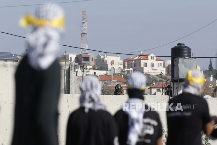  Pengunjuk rasa Palestina menyaksikan pasukan Israel selama bentrokan setelah demonstrasi menentang permukiman Israel di desa Kofr Qadom, dekat kota Nablus, Tepi Barat utara, 1 Januari 2021. Pihak berwenang Israel sedang bekerja untuk membangun lebih dari 17 ribu unit permukiman di Yerusalem. Ilustrasi. 